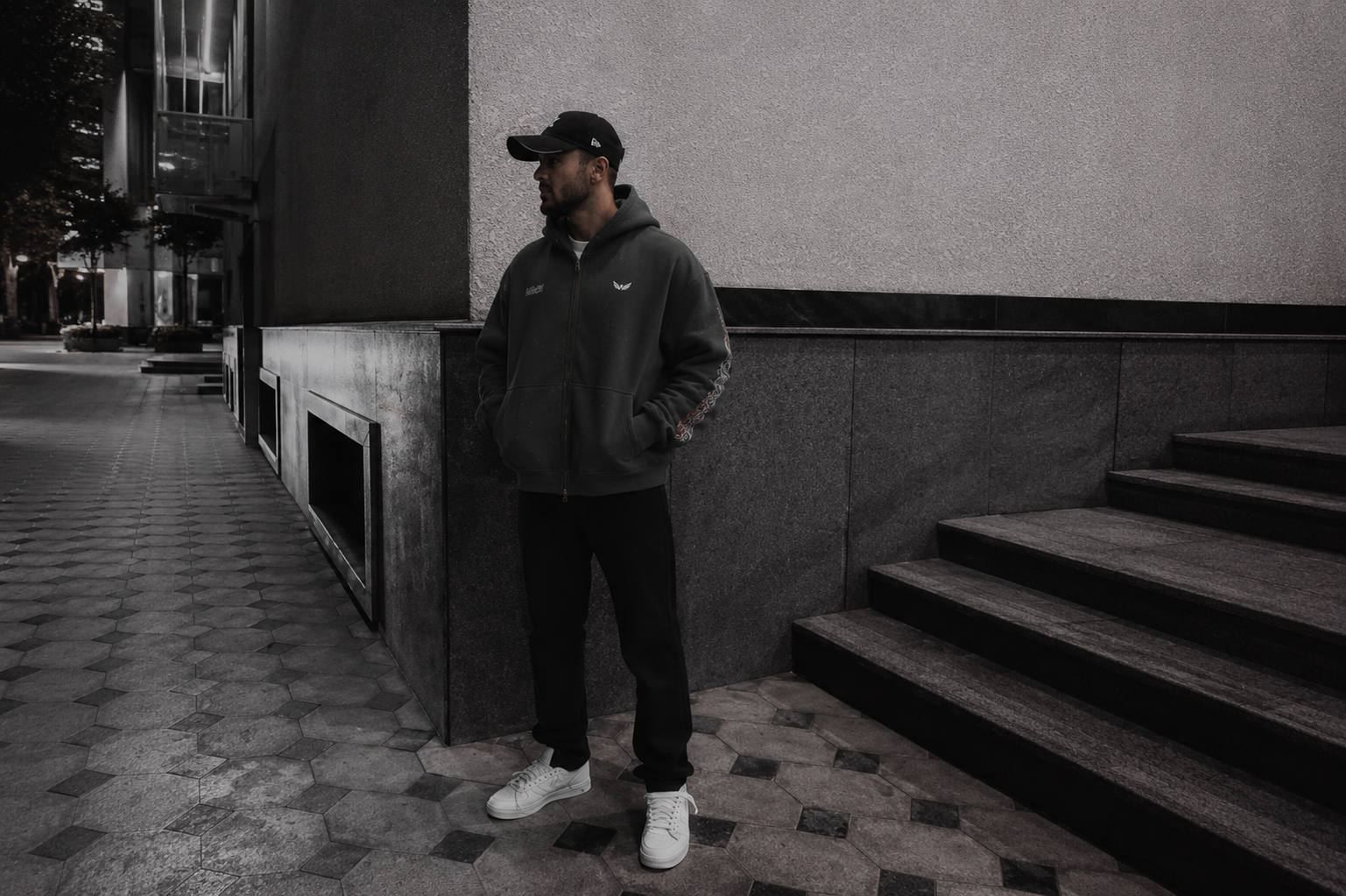 Model wearing a heavyweight oversized zip hoodie in a modern urban setting at night, showcasing premium Australian streetwear style for 2026.